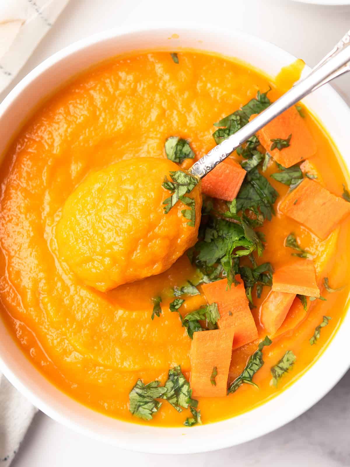 Close-up of creamy carrot apple ginger soup garnished with herbs and ready to serve for the dinner