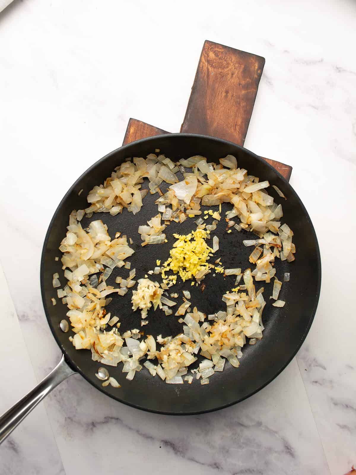 Chopped onion and garlic sautéing in a pot with butter