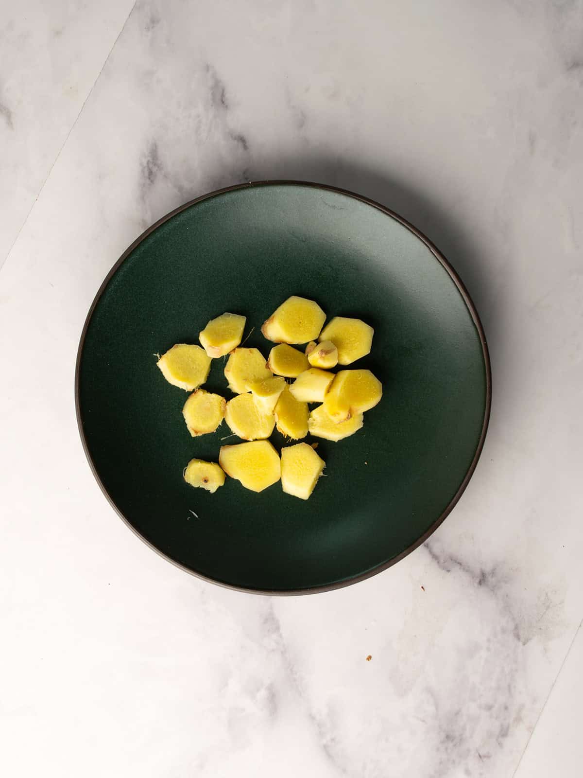 Sliced fresh ginger and lemon on a cutting board.
