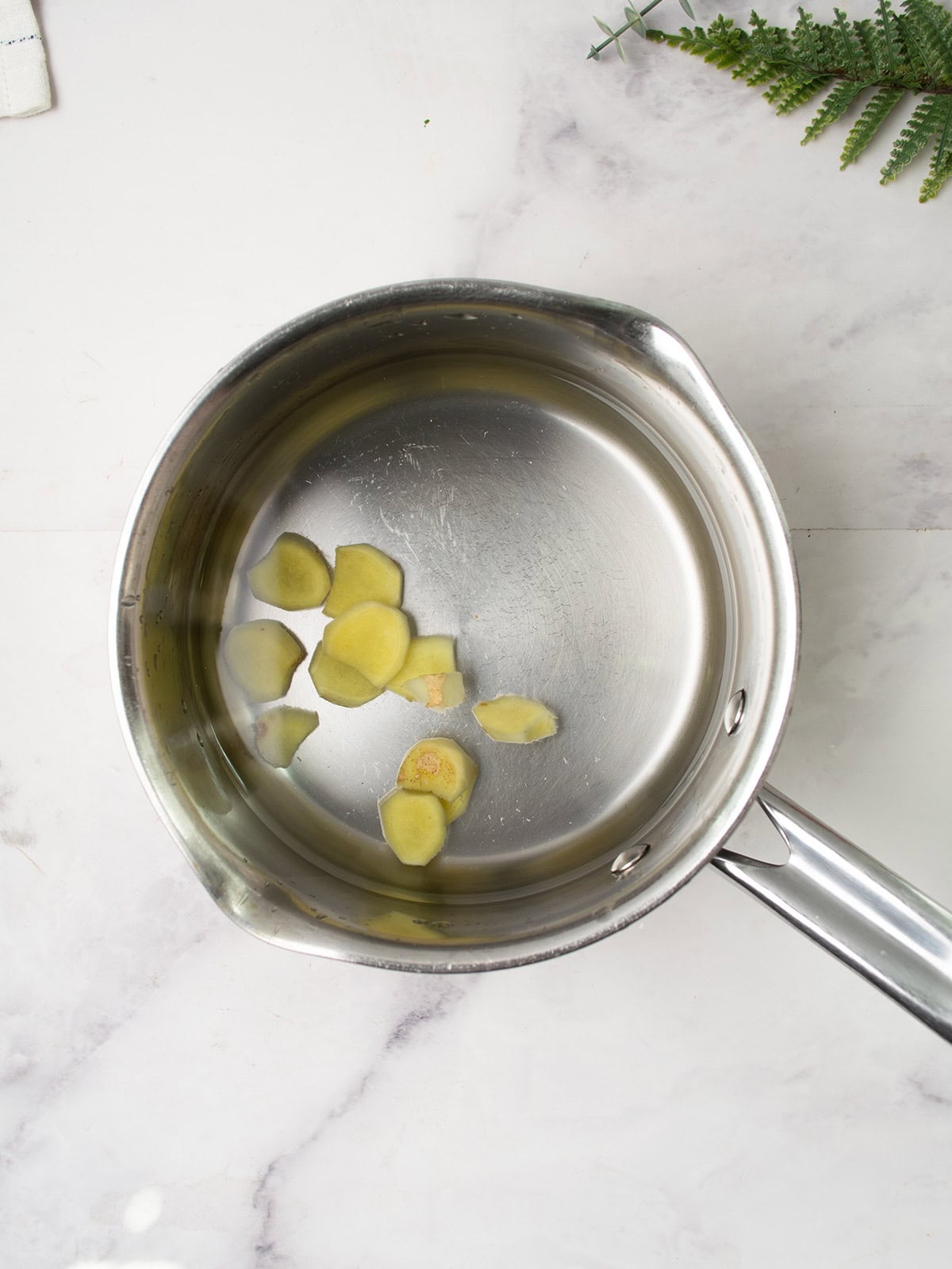 Ginger and lemon boiling in hot water in a saucepan.