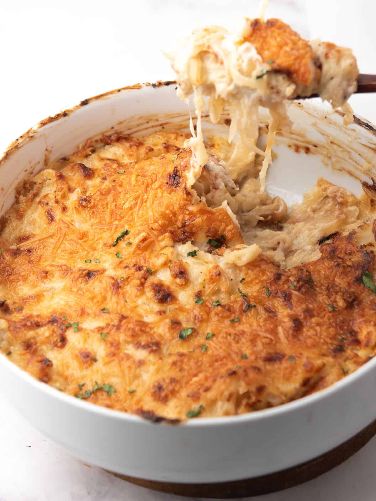 reamy onion dip in a baking dish, garnished with extra Parmesan and breadcrumbs.