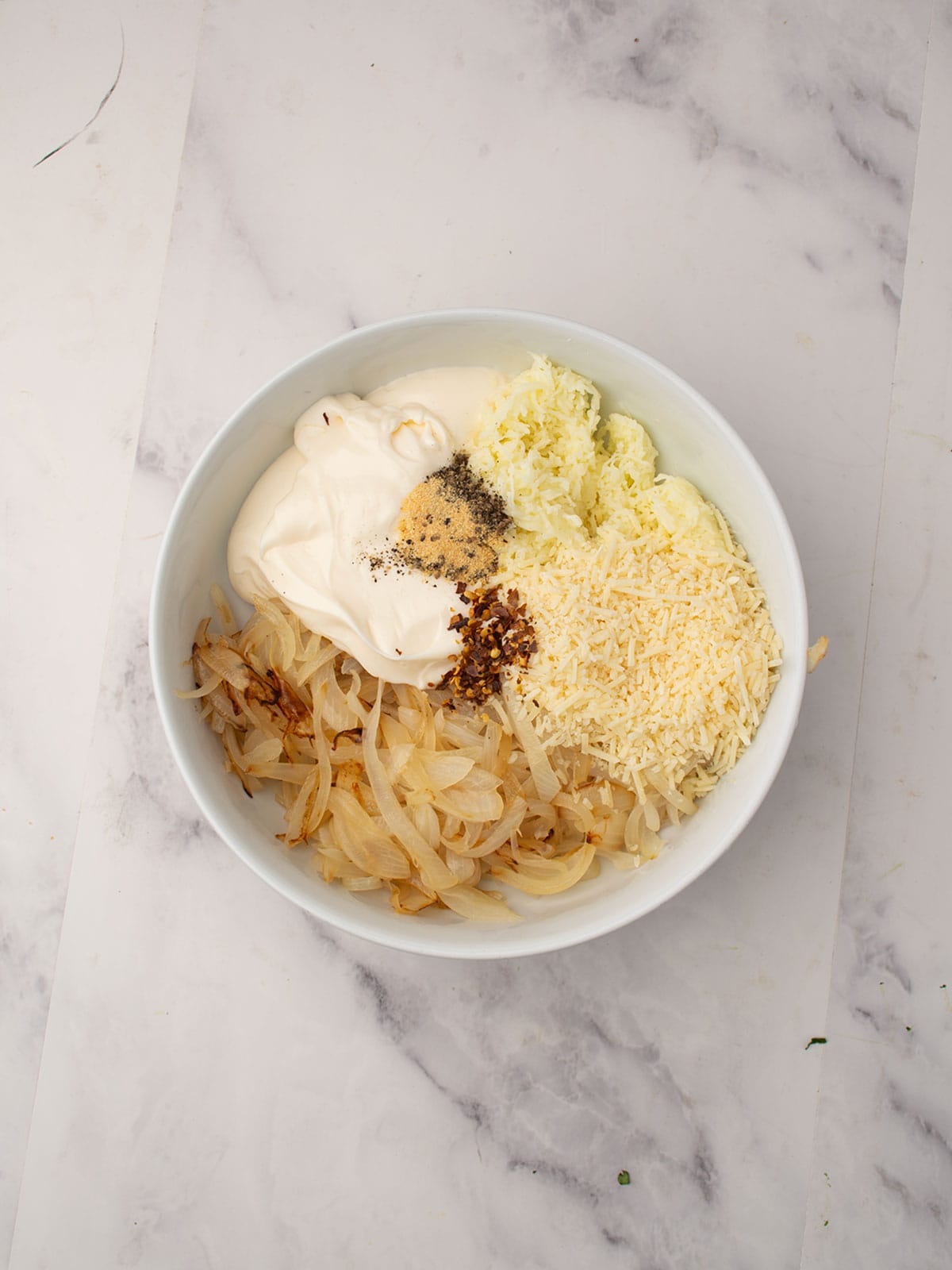 Mixing cream cheese, mayonnaise, mozzarella, and spices in a bowl for dip