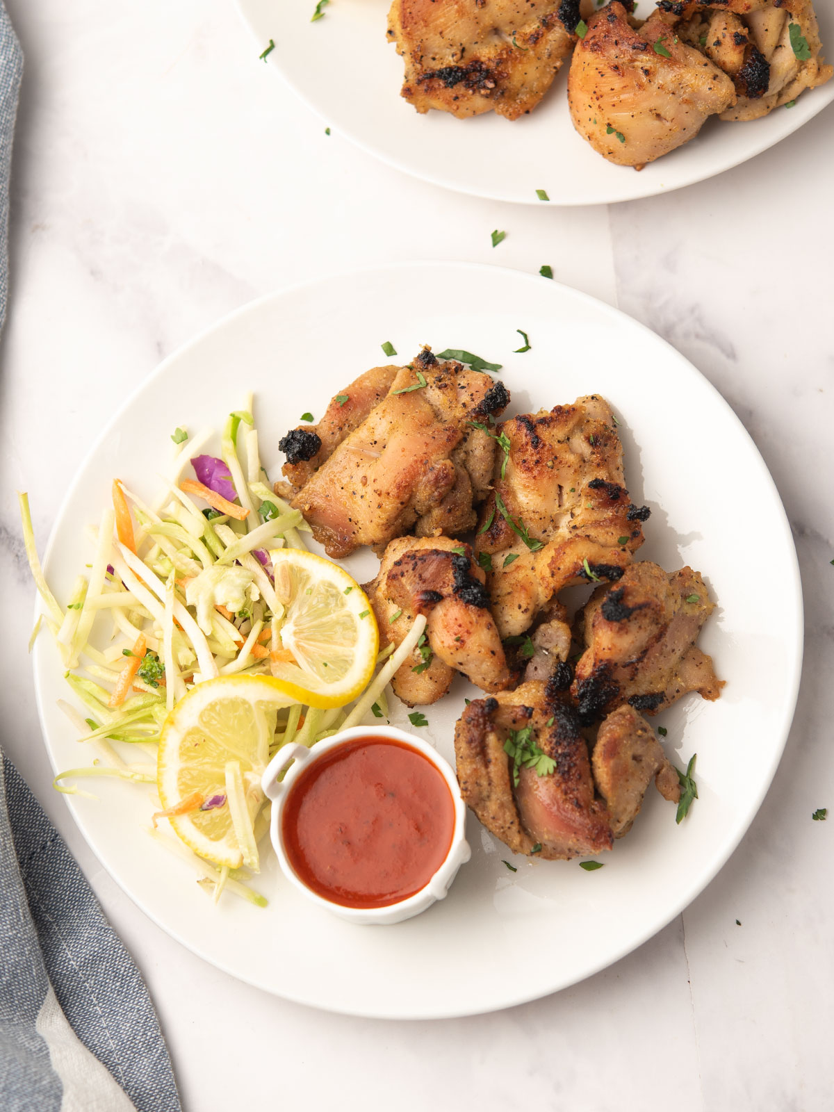 Close-up of grilled lemon pepper chicken skewers with fresh herbs and lemon wedges.