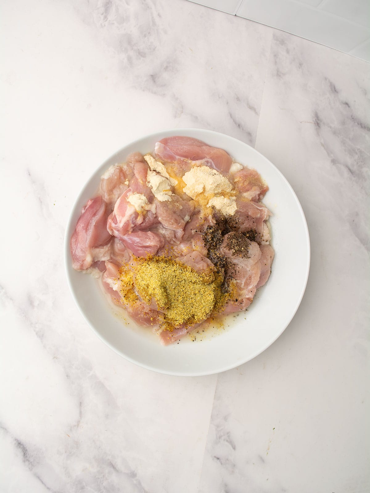 Chicken cubes being tossed in marinade for lemon pepper chicken skewers.