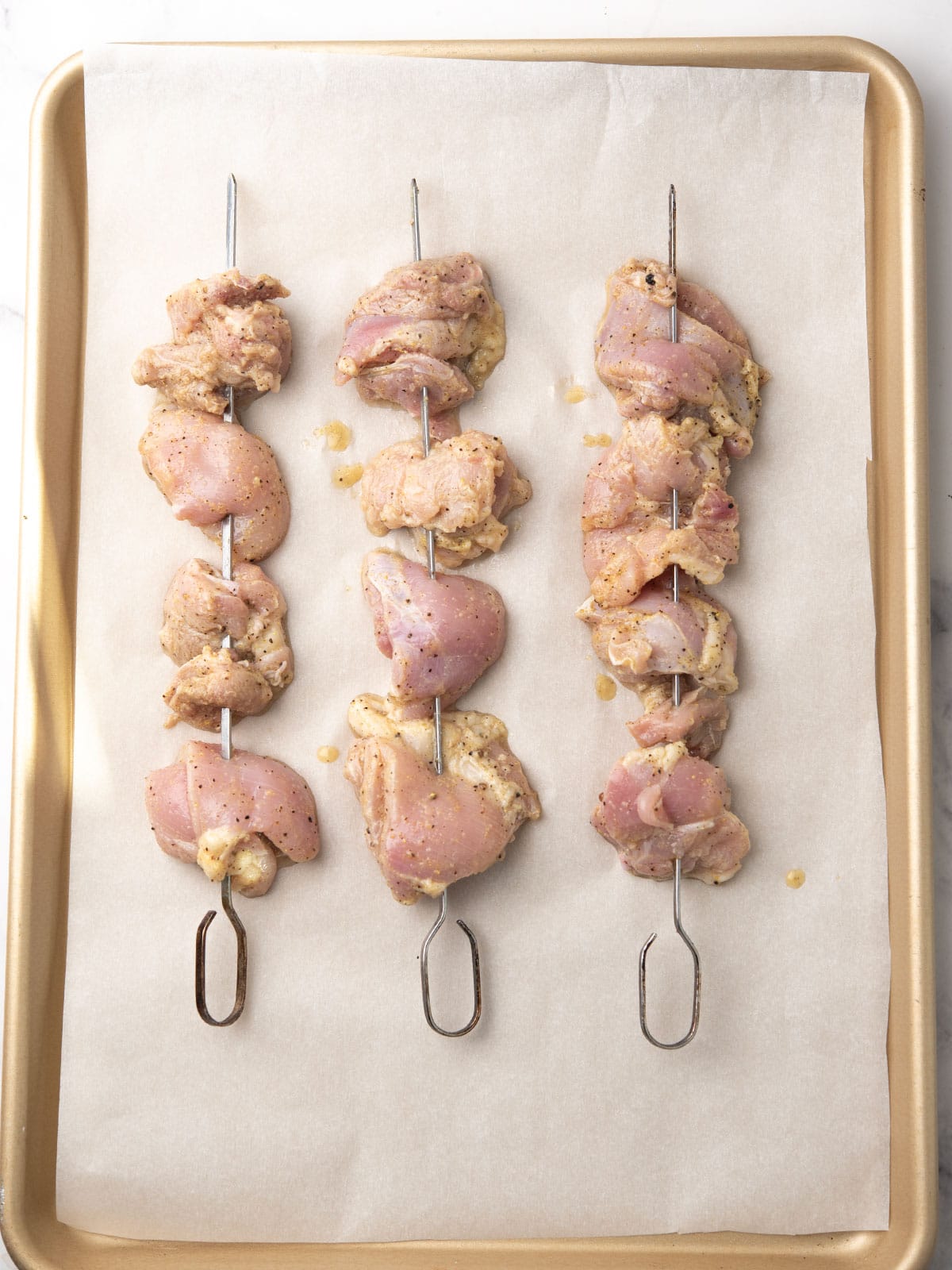 Chicken pieces threaded onto soaked wooden skewers ready for grilling.