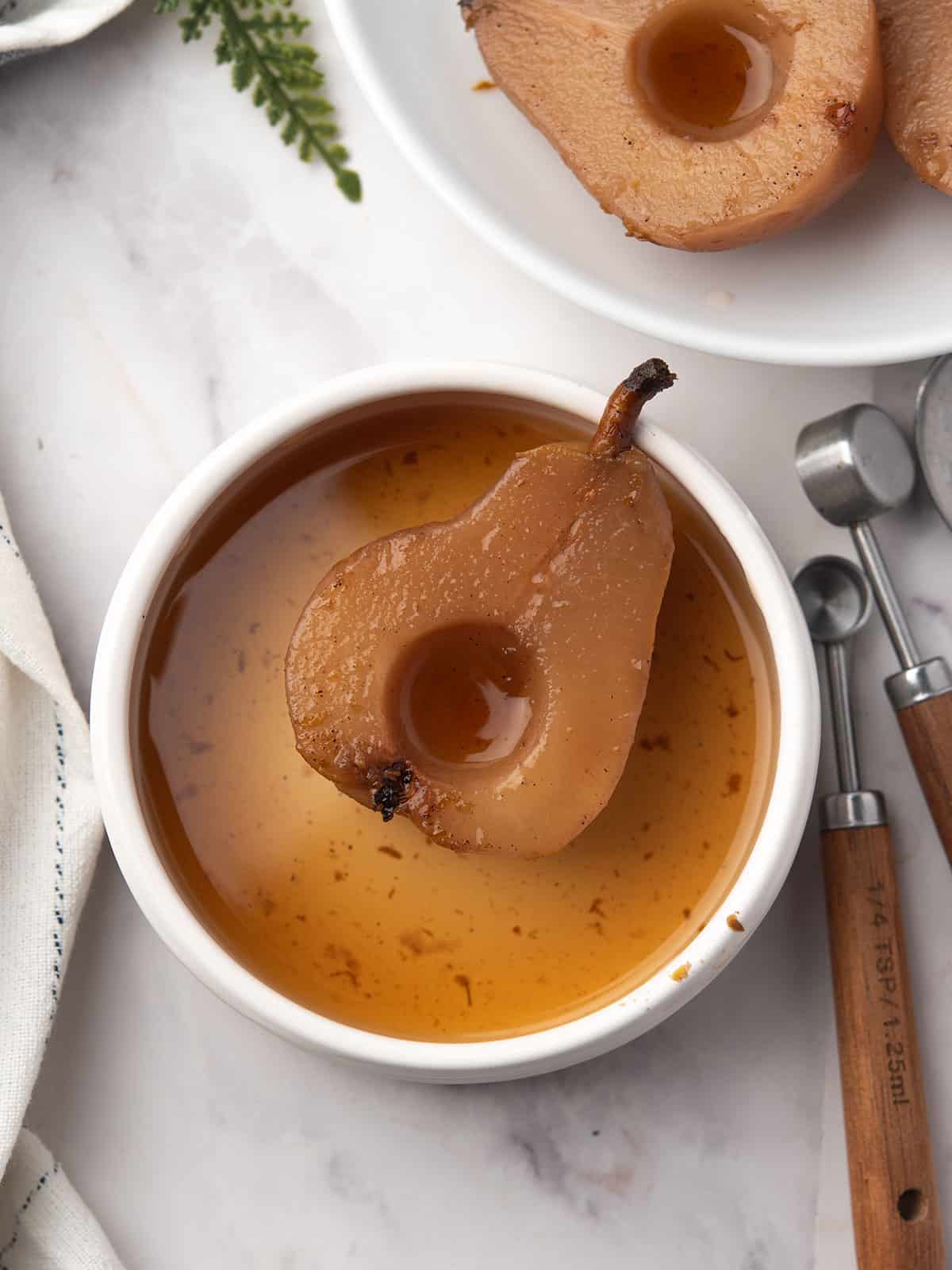 Close-up of tender spiced pears garnished with syrup and orange zest.