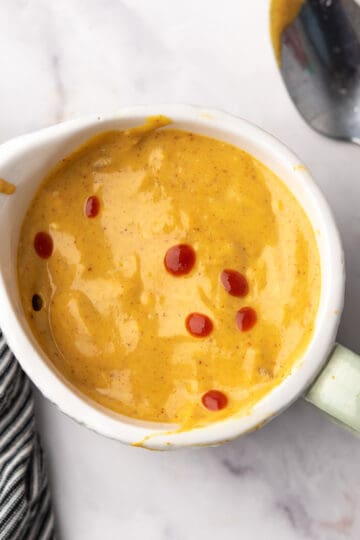 Homemade spicy honey mustard sauce in a small jar, with the spoon