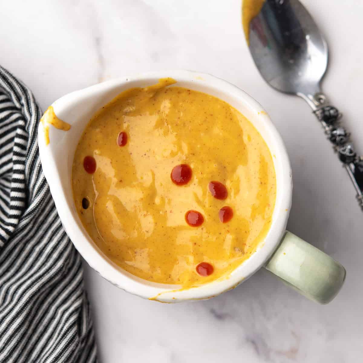 Homemade spicy honey mustard sauce in a small jar, with the spoon