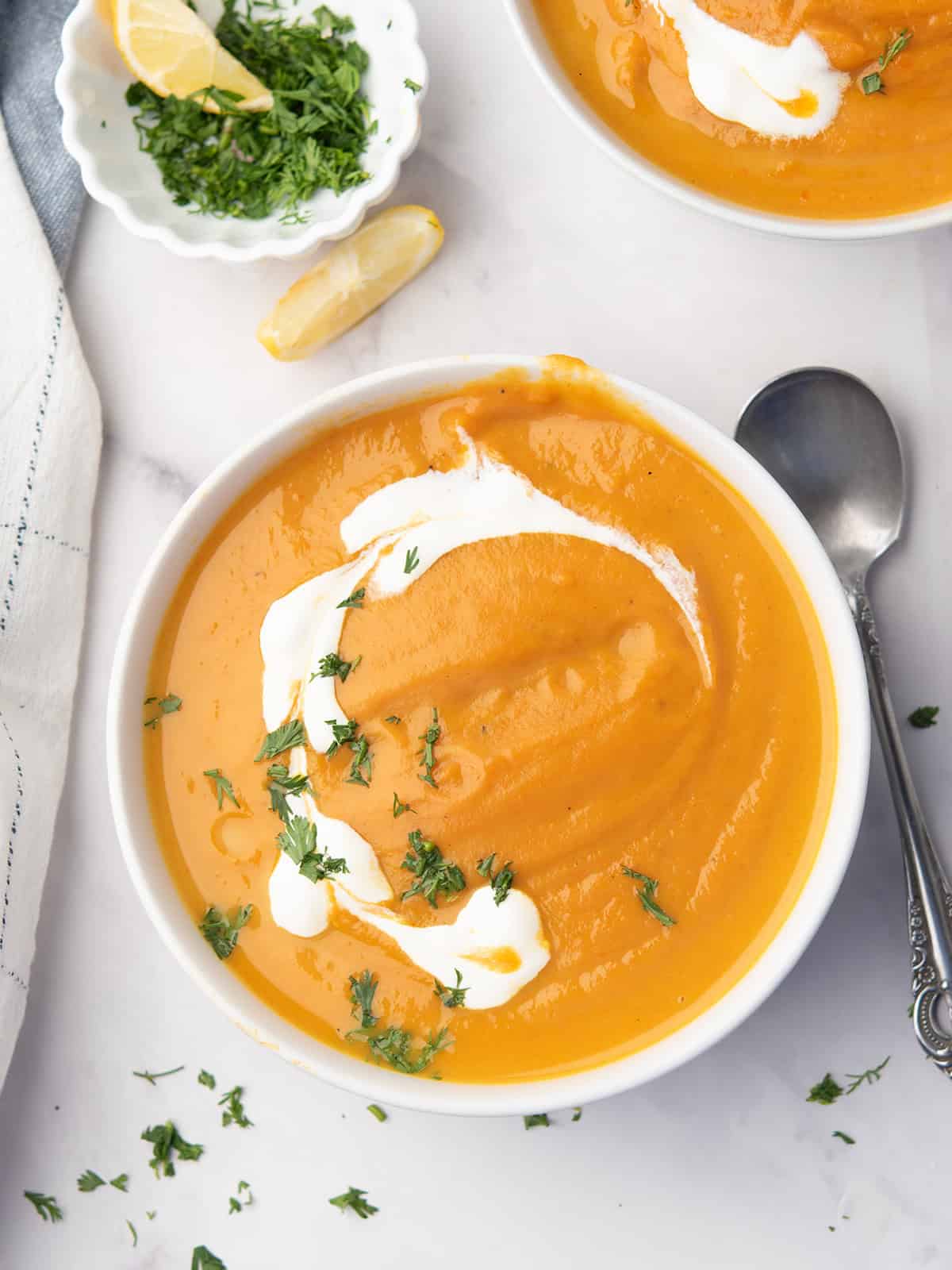Bowl of creamy sweet potato and carrot soup with fresh herbs