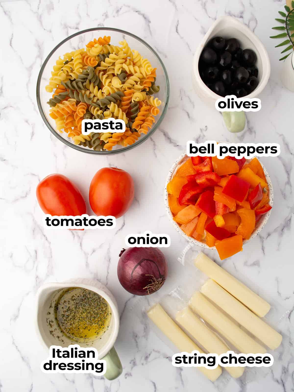 Ingredients for Halloween Pasta Salad including pasta, tomatoes, olives, and bell peppers.