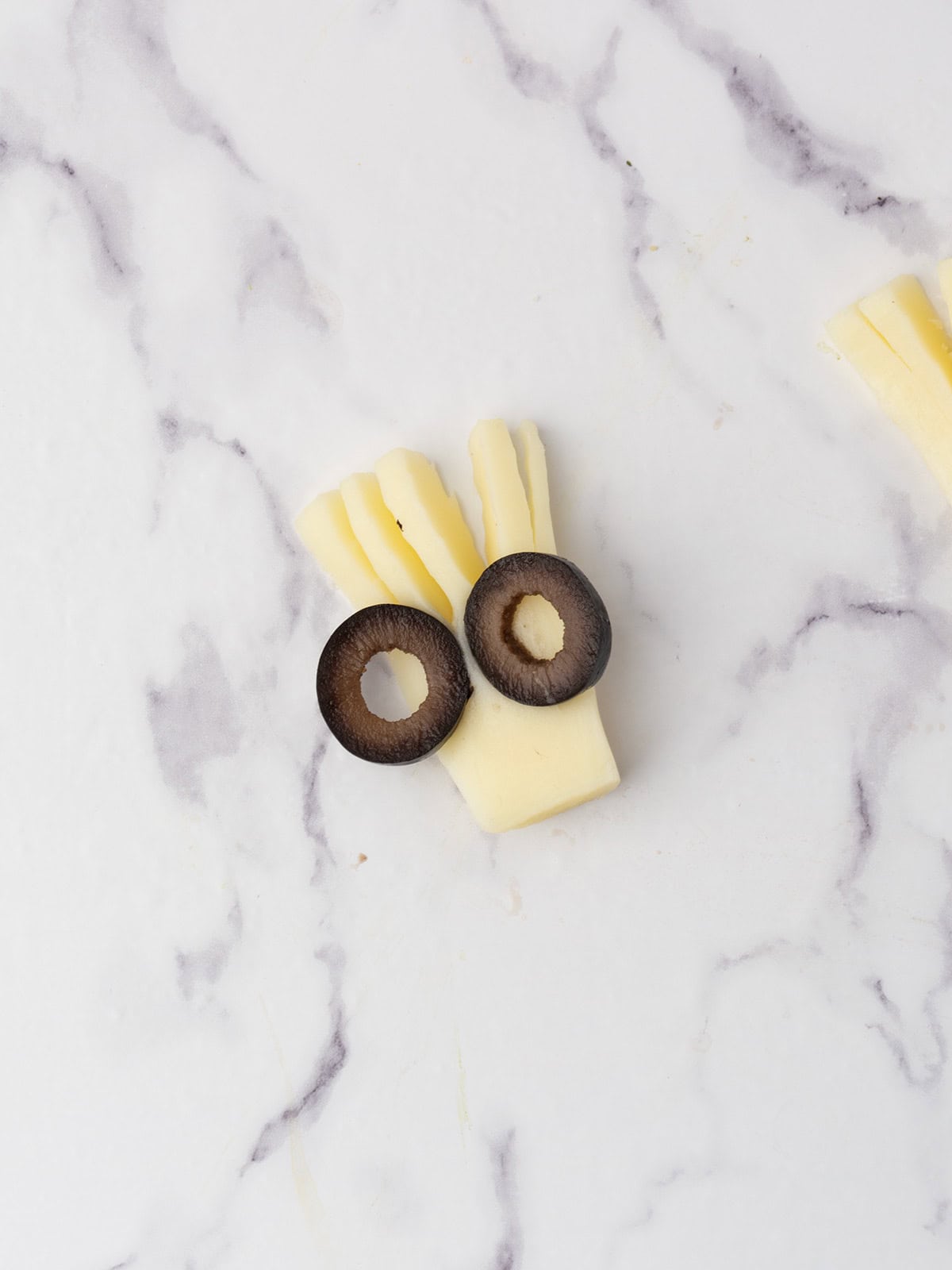 pressing the olives into the cheese heads