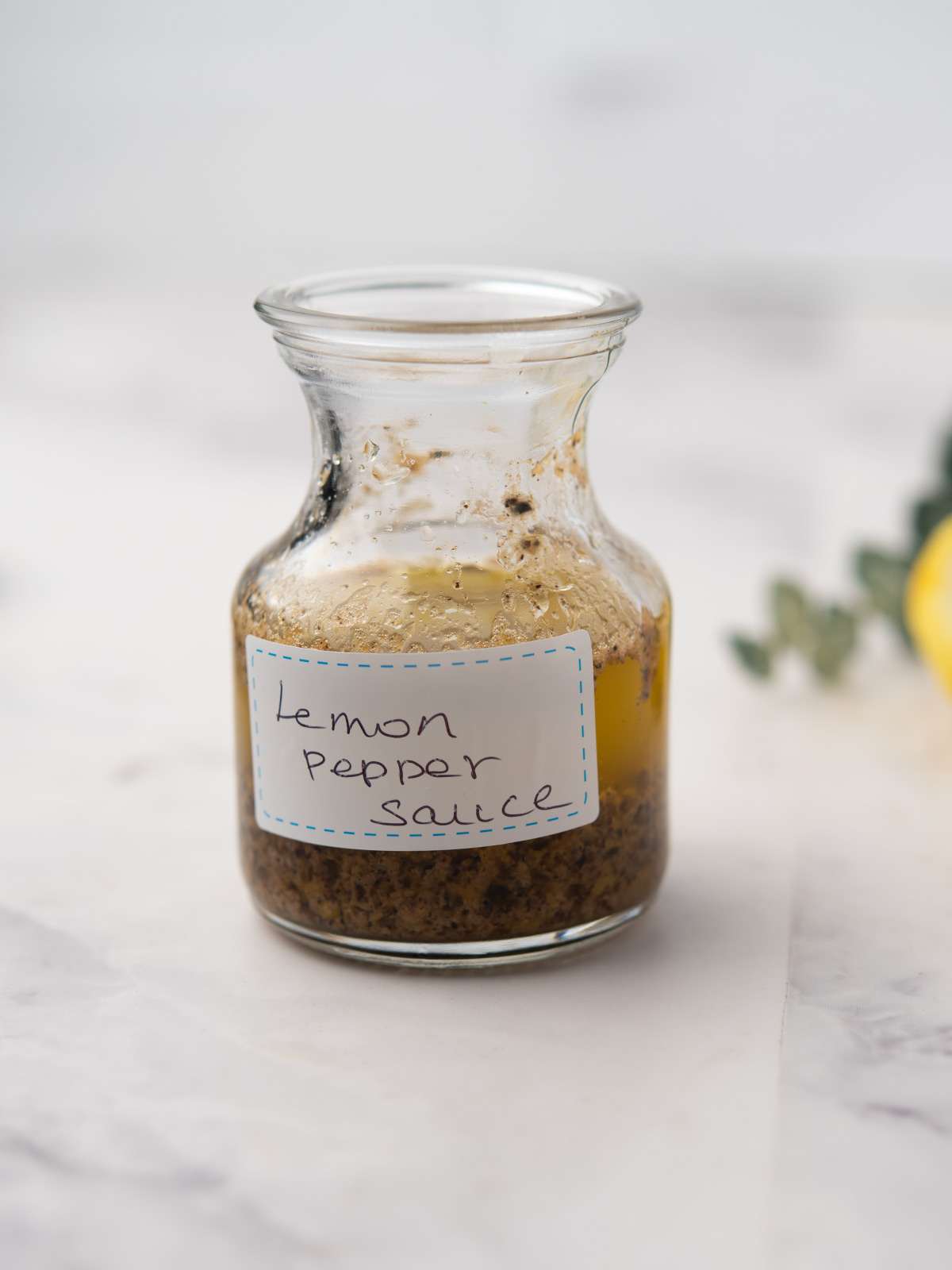 Delicious jar of lemon pepper sauce with fresh lemon slices