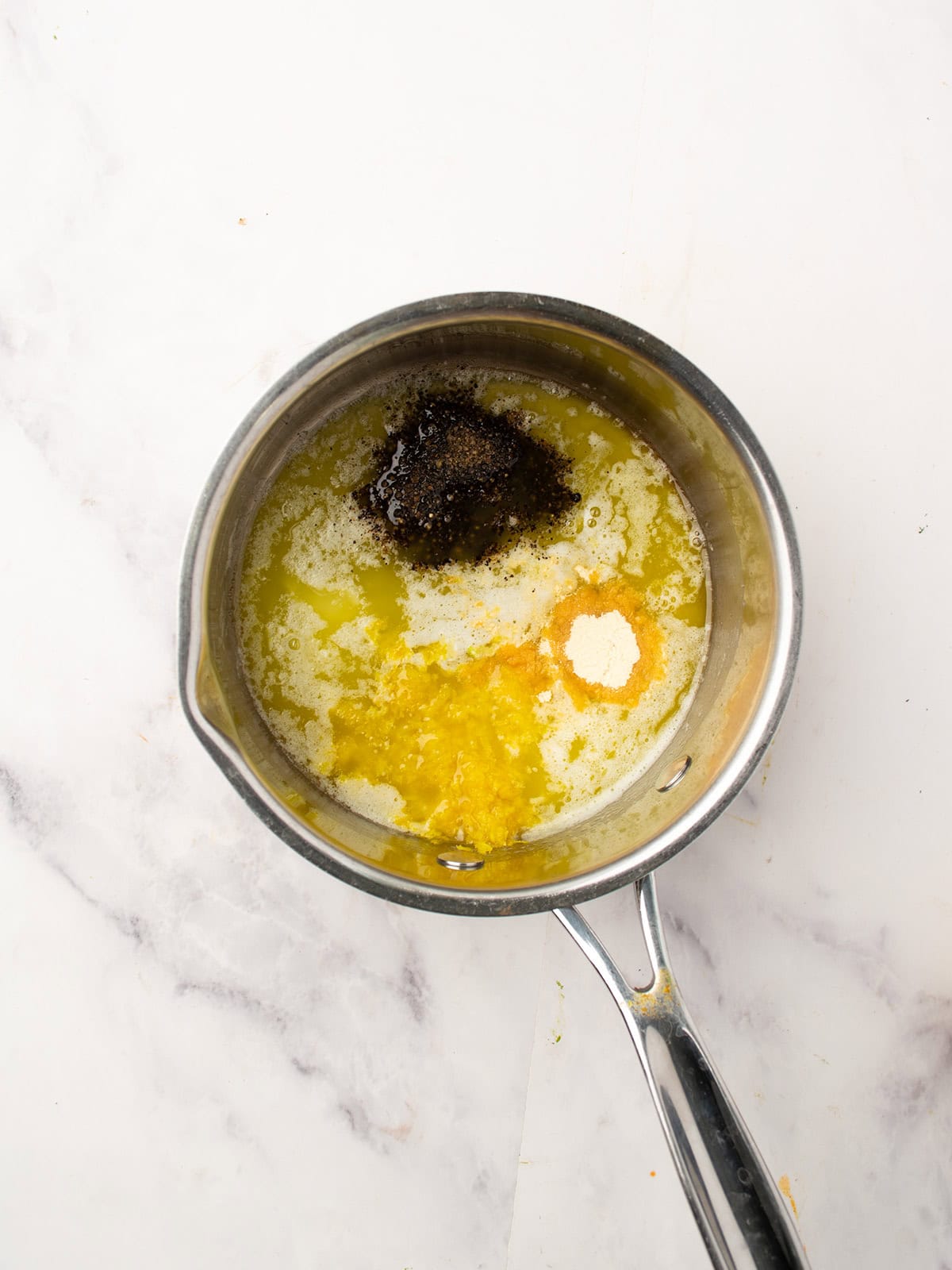 Stirring in lemon zest and lemon juice into the melted butter mixture.