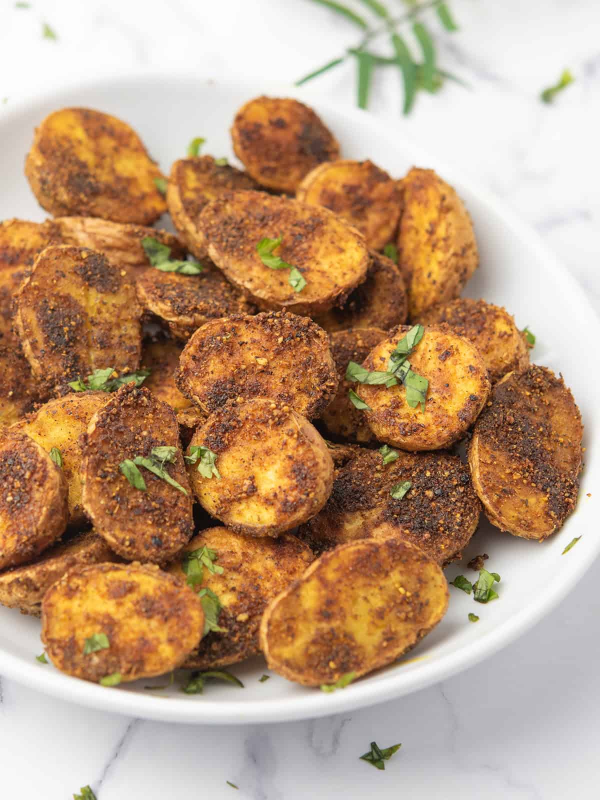 Golden crispy roasted potatoes with spices on a plate.