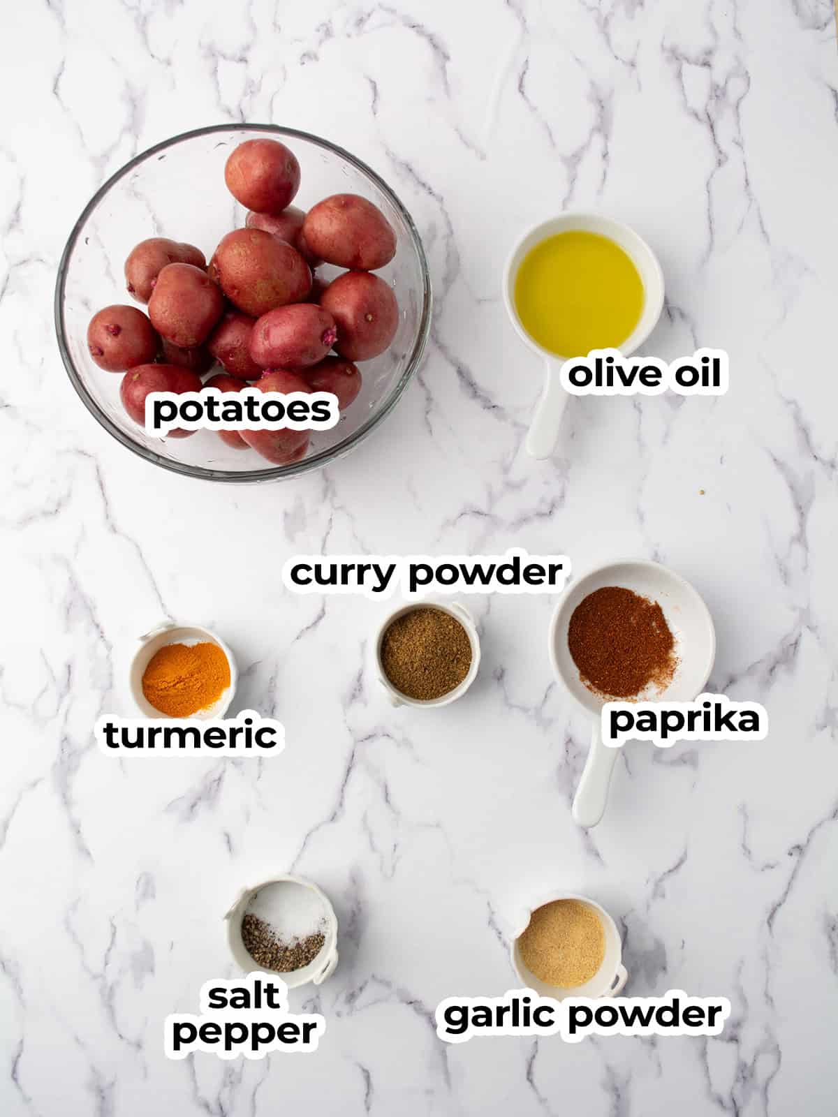 Ingredients for spicy roasted potatoes including potatoes, onions, garlic, and spices.