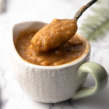 cajun gravy in a white cup and a spoon