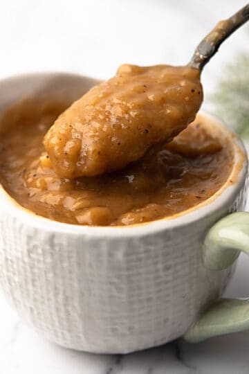 cajun gravy in a white cup and a spoon