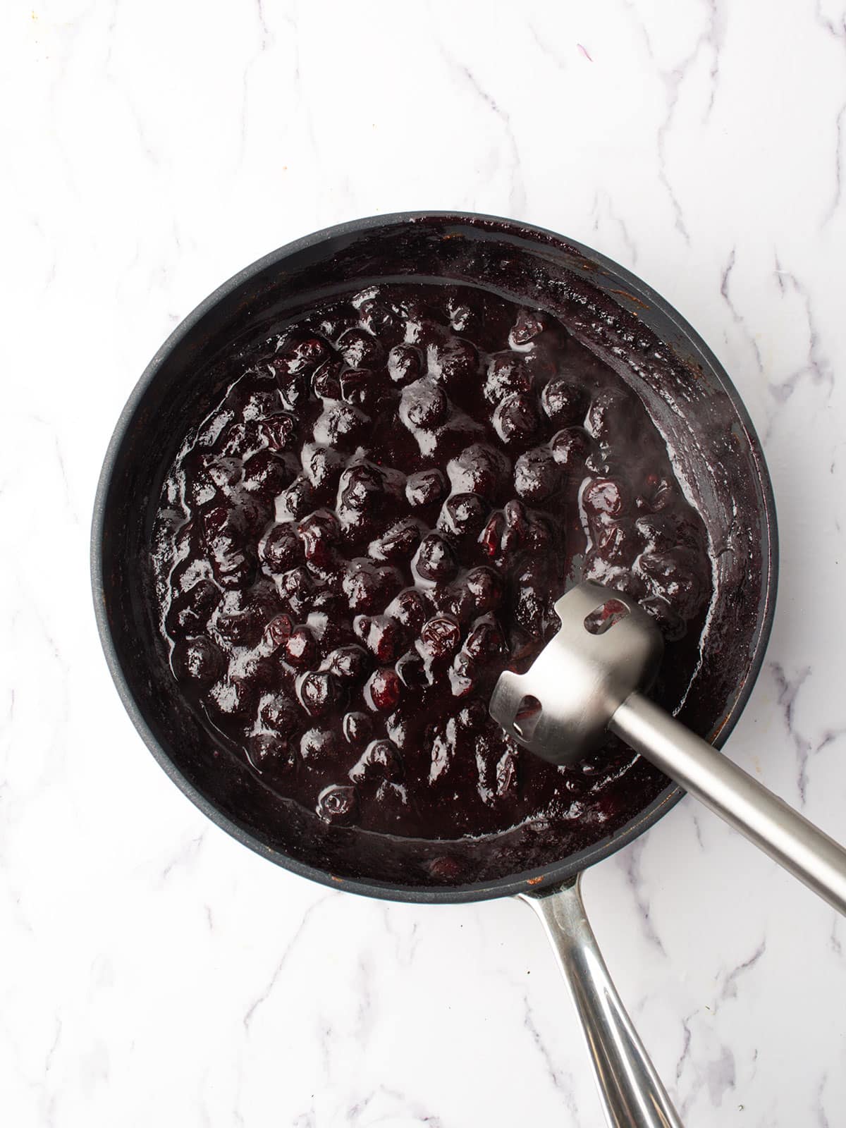 mashing the blueberries with the hand blender.