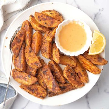 spicy potato wedges are looking crispy and golden brown served with dipping sauce.
