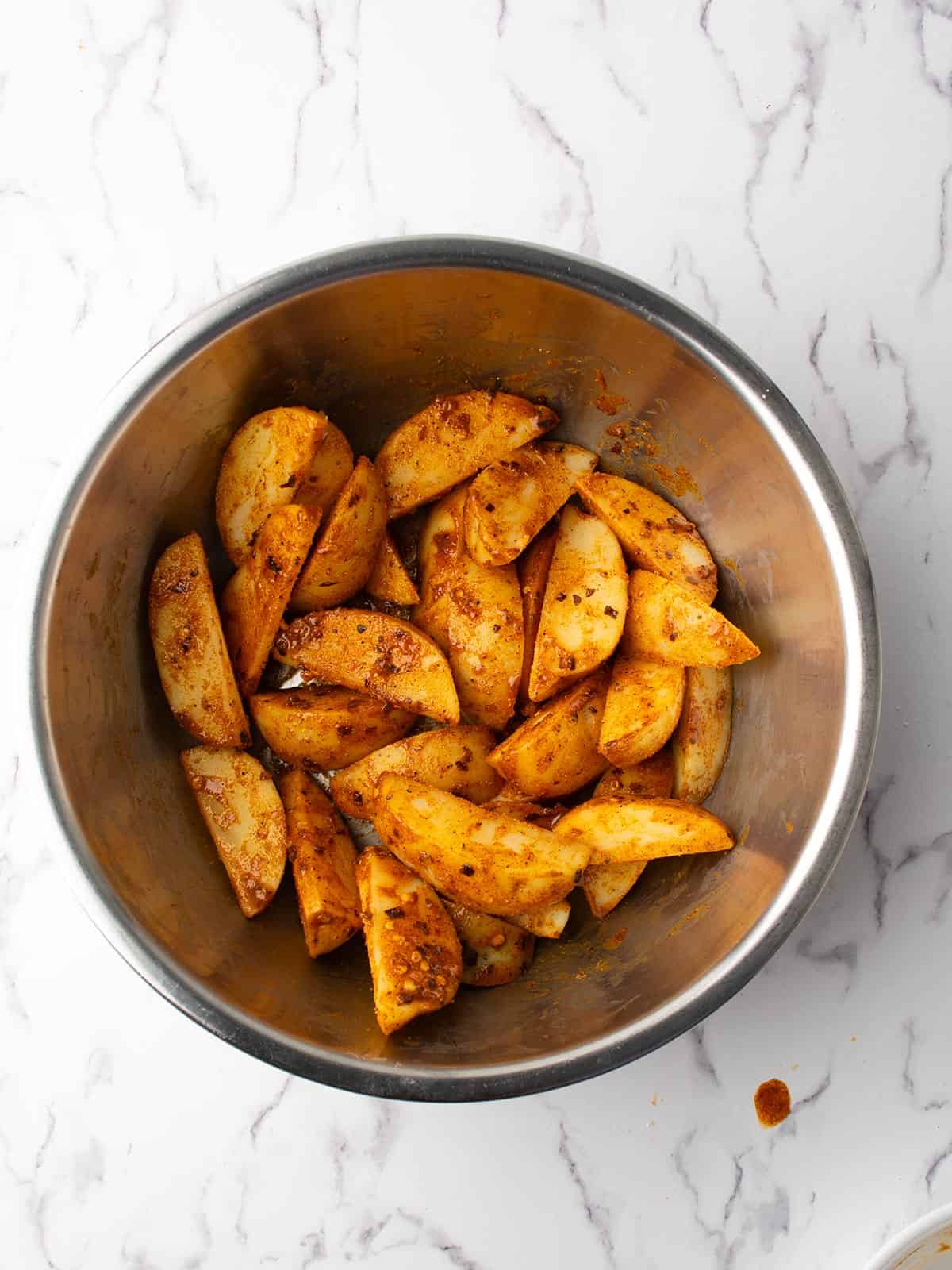 the uncooked spicy potato wedges are ready for baking.