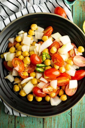 Tomato chickpea salad, one of the spicy side dish recipes, was placed on the dinner table.