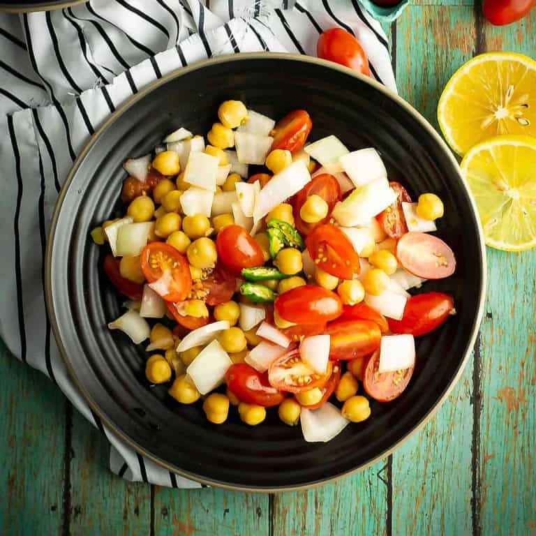Tomato chickpea salad, one of the spicy side dish recipes, was placed on the dinner table.