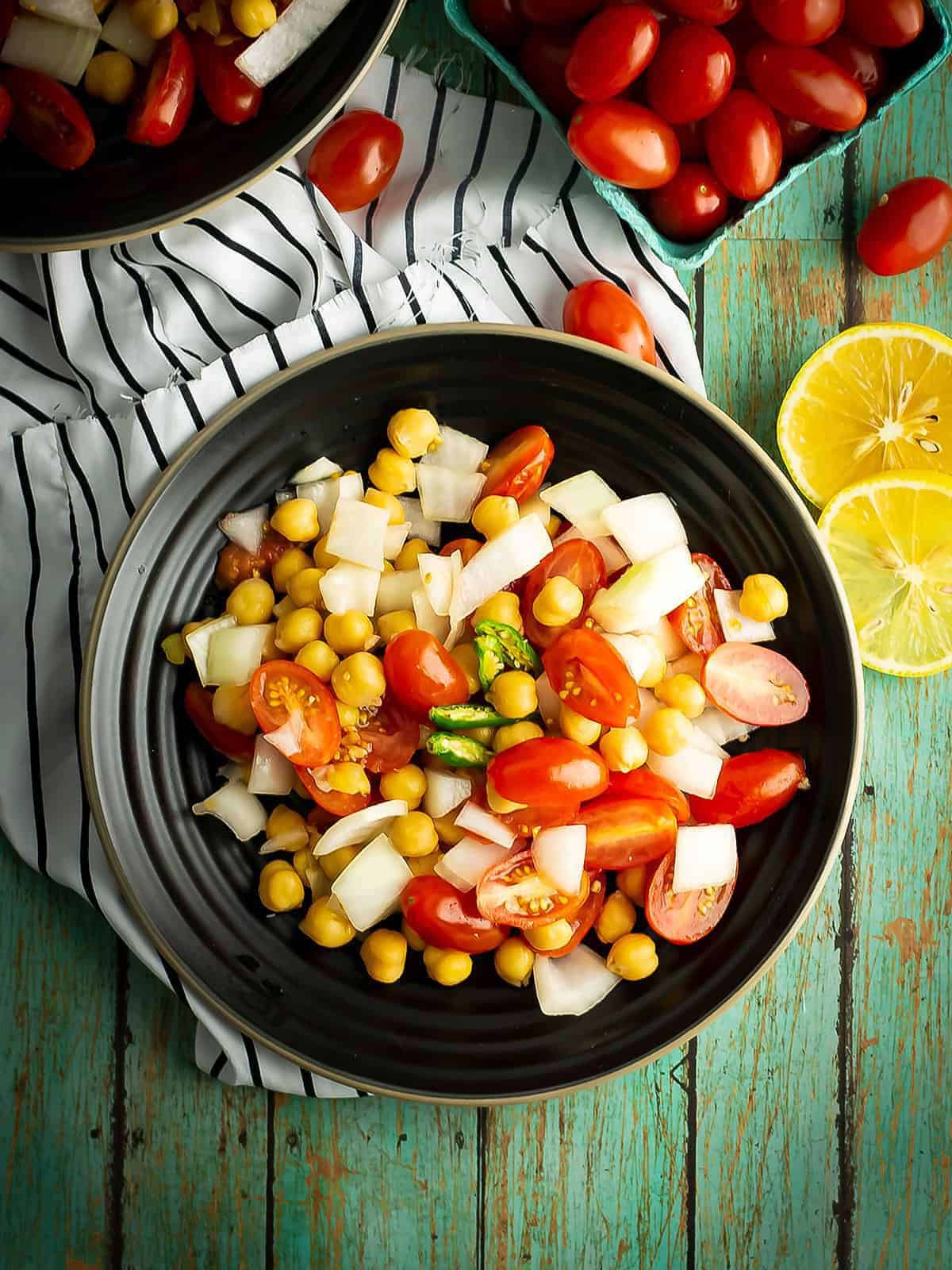 a salad with tomato and chickpea served as a spicy side dish
