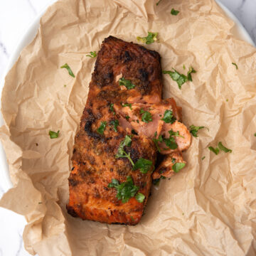 Close-up of flaky baked blackened salmon with Cajun spice crust garnished with parsley