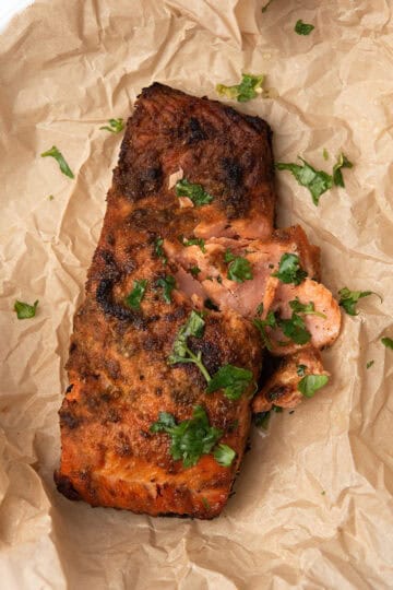 Close-up of flaky baked blackened salmon with Cajun spice crust garnished with parsley