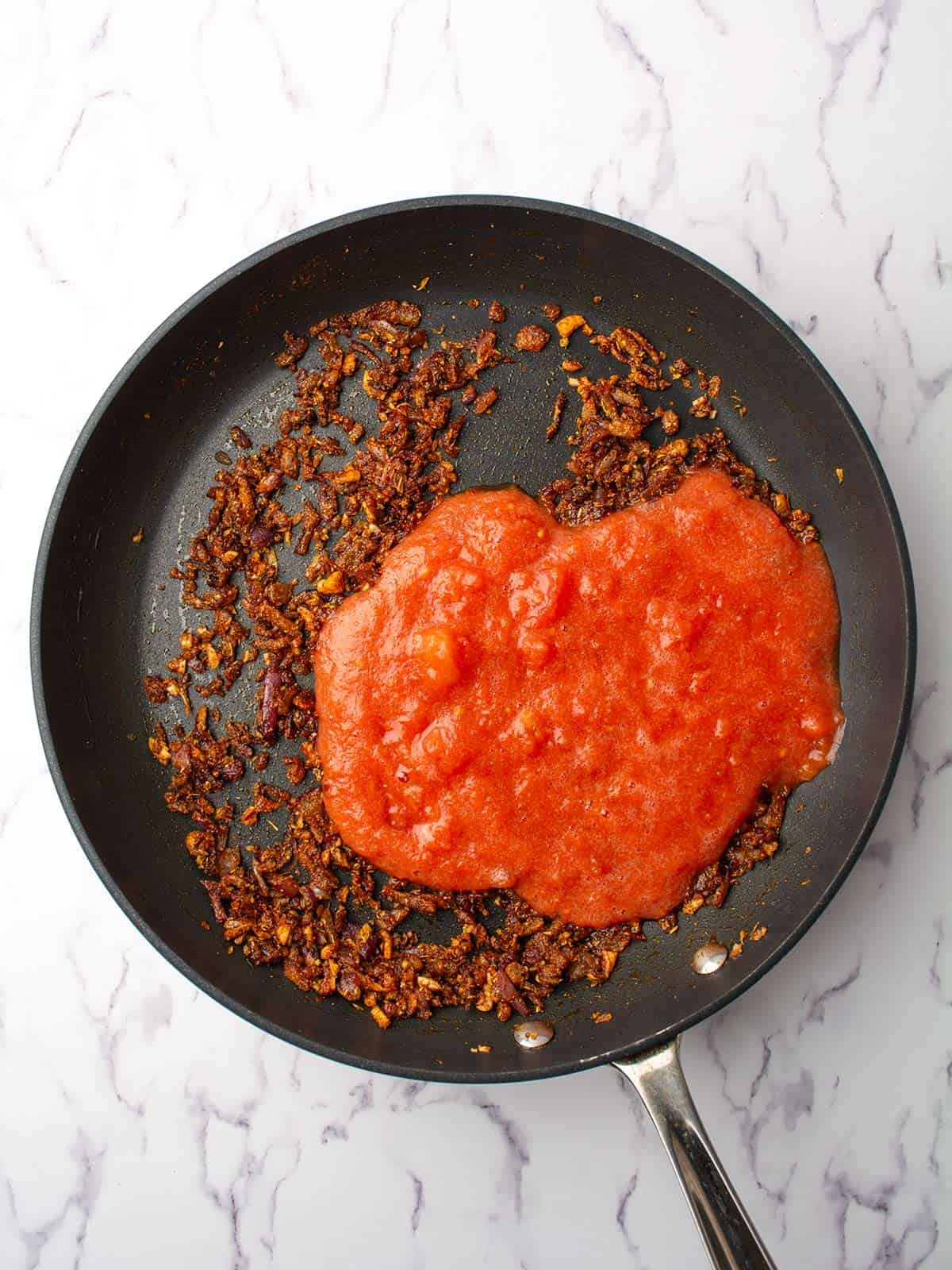 crushed tomatoes added to the pan.