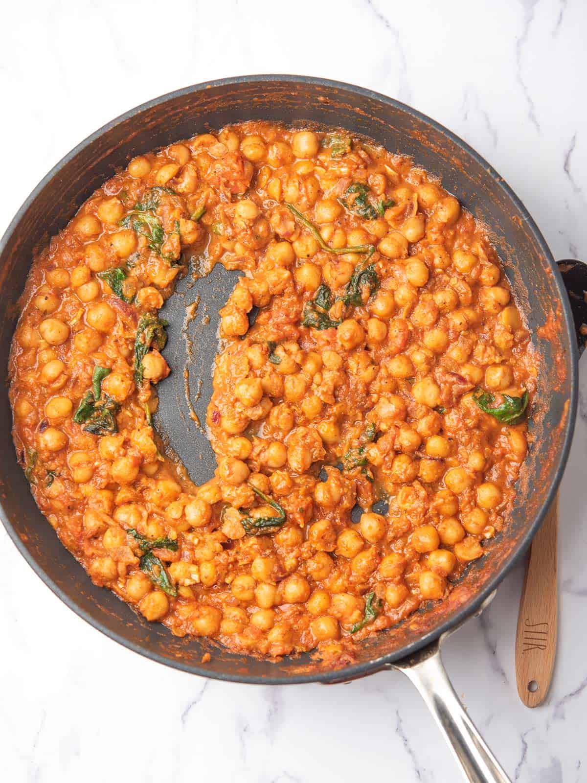creamy harissa chickpeas with caramalized onion in the pan.