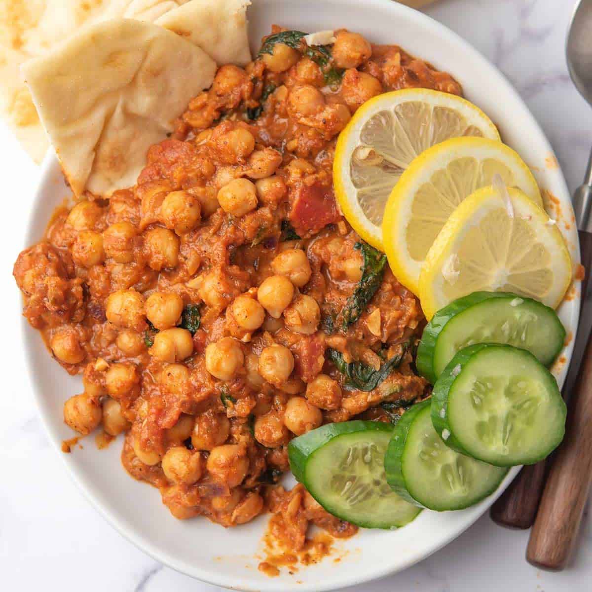 creamy harissa chickpeas with caramalized onion served with lemon, bread and veggies