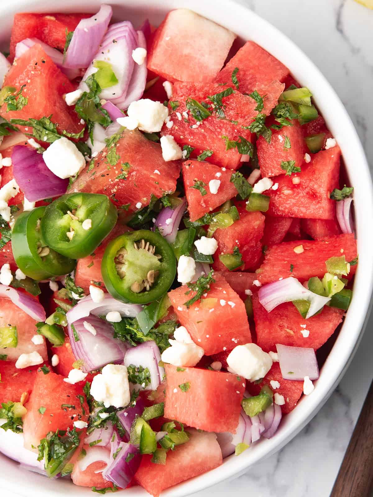 watermelon jalapeno salad garnished with jalapeno slices and geta cheese.
