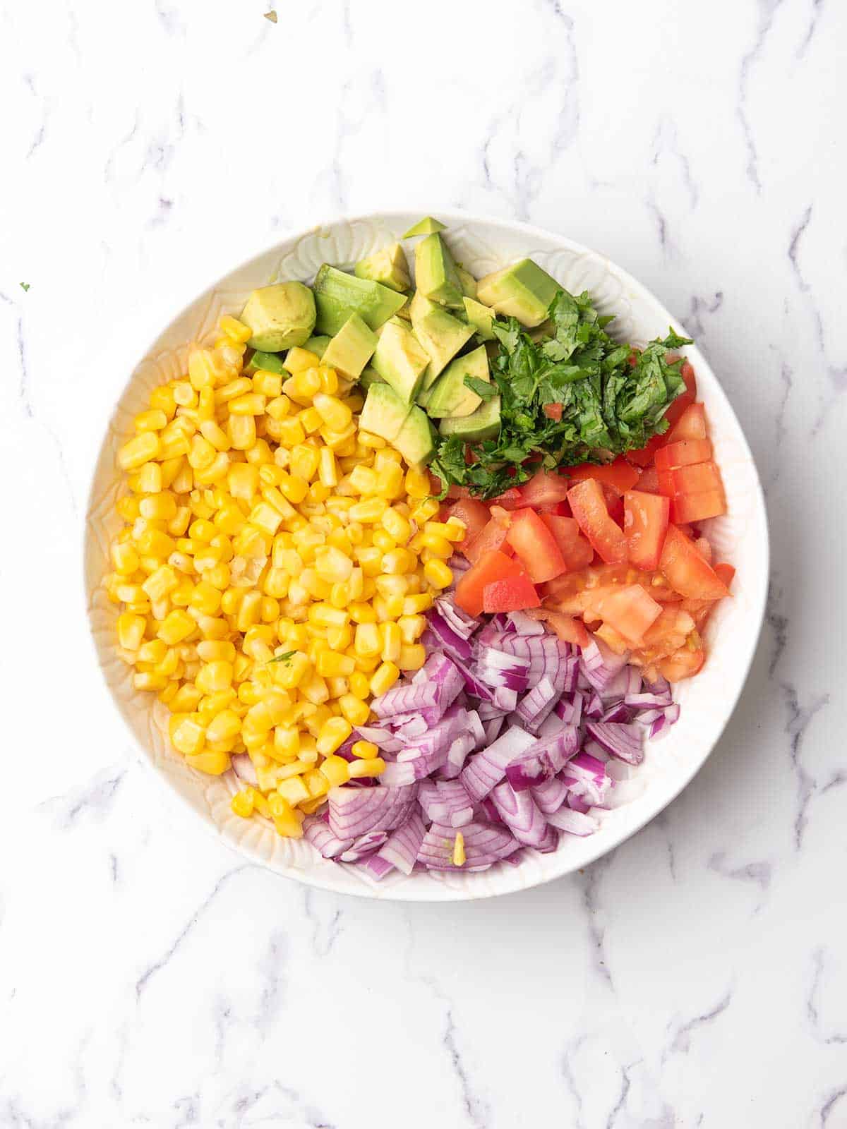 the corn, onion, tomato, avocado, cilantro kept ready in a bowl.