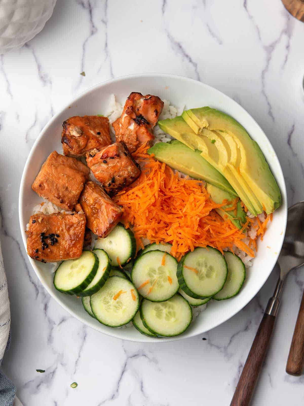 the salmon and the veggies are arranged in the spicy salmon bowl.