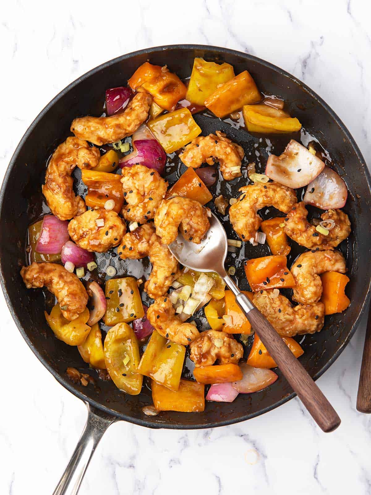 Airfryed firecracker shrimp served in a pan garnished with roasted sesame seeds.