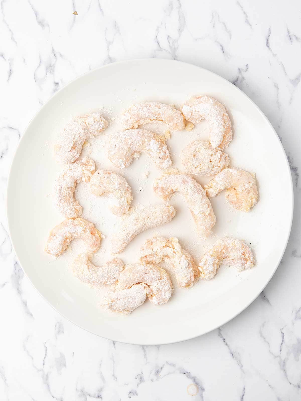 corn starch coated shrimp are placed in a plate for airfrying.