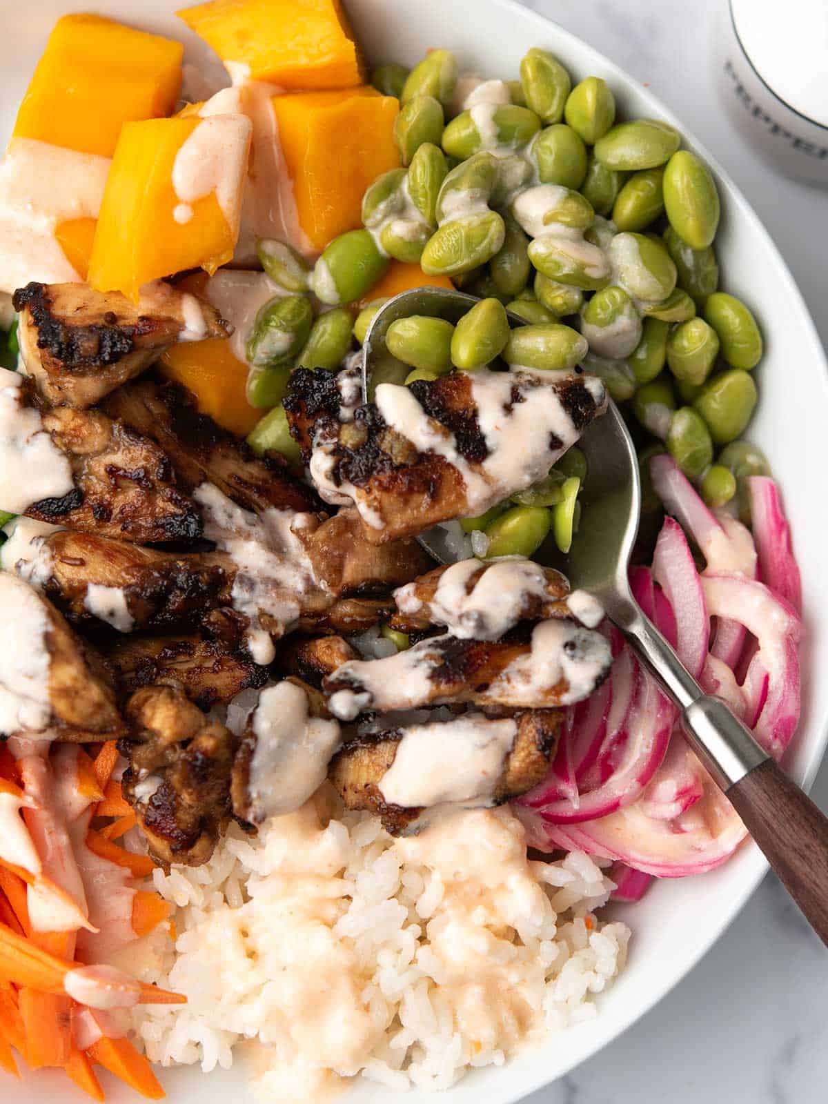 the juicey tender chicken in the teiyaki chicken poke bowl with the edamame, rice, and pickled onion.