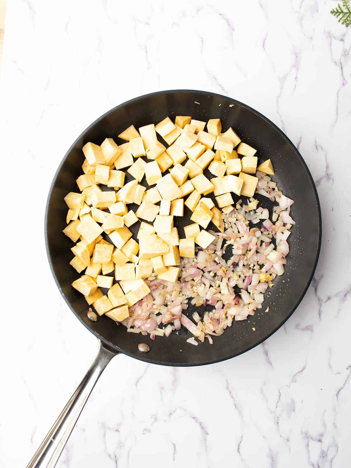 Cubed sweet potatoes and onion in the skillet.