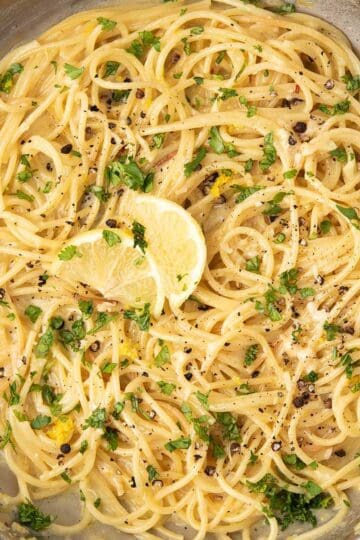 lemon pepper pasta garnished with lemon slices and parsley, and freshly ground black pepper.