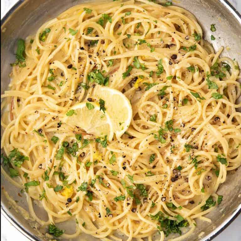 lemon pepper pasta garnished with lemon slices and parsley, and freshly ground black pepper.