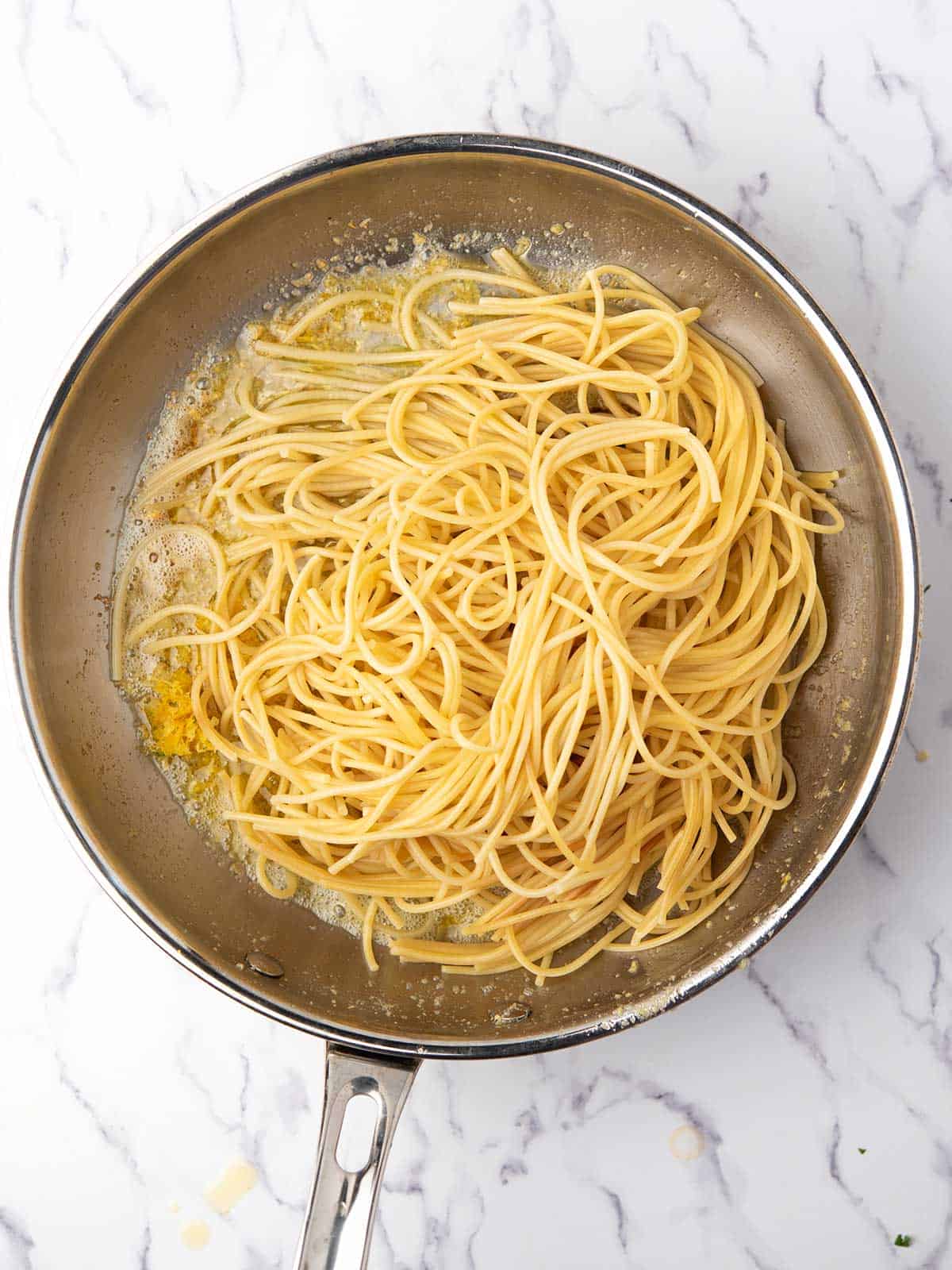 Adding spaghetti to the lemon pepper sauce.
